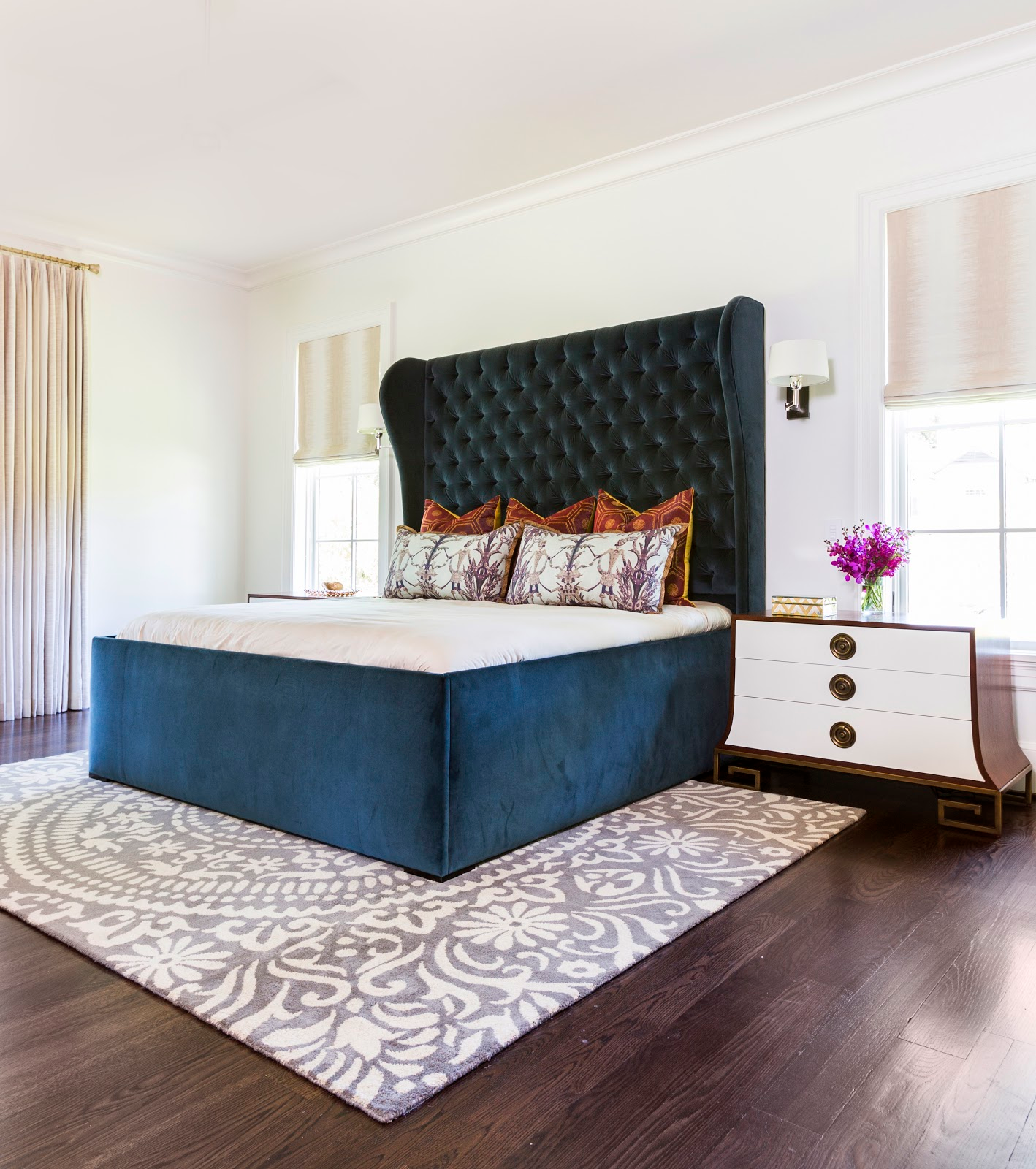 Blue velvet tufted headboard with organic neutral rug in master bedroom - laura u interior design